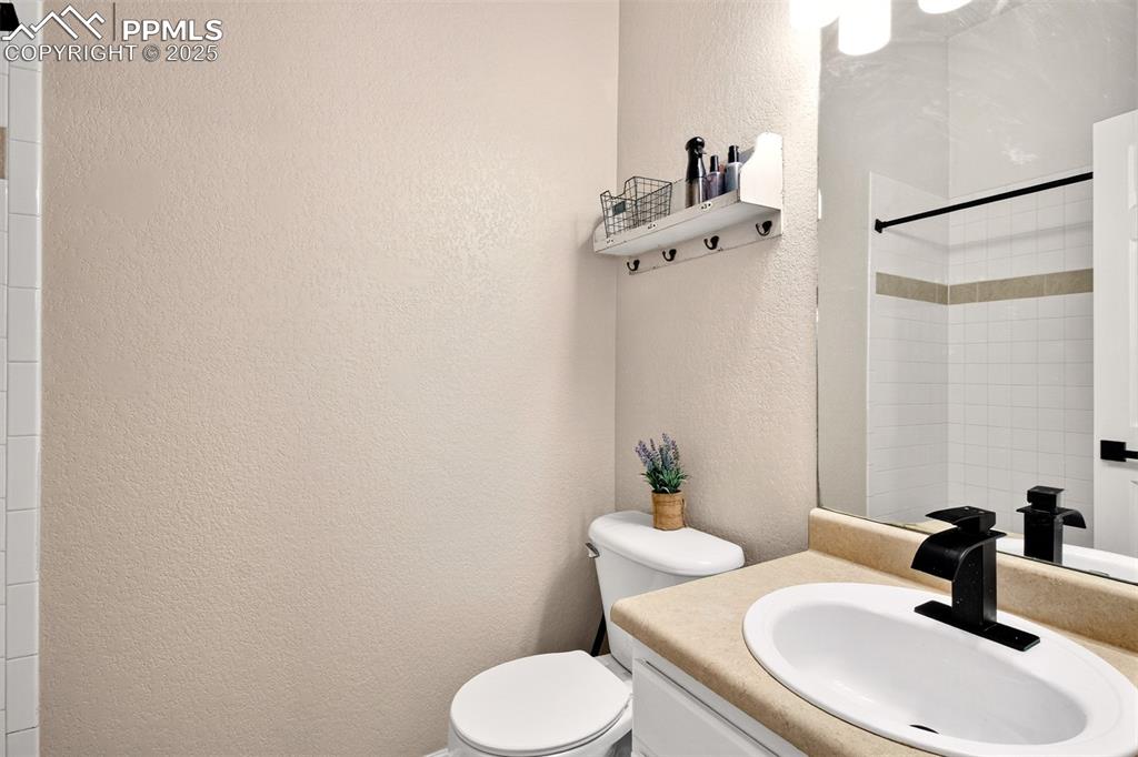 Bath adjoins primary bedroom with a textured wall, vanity, and a shower/tub.