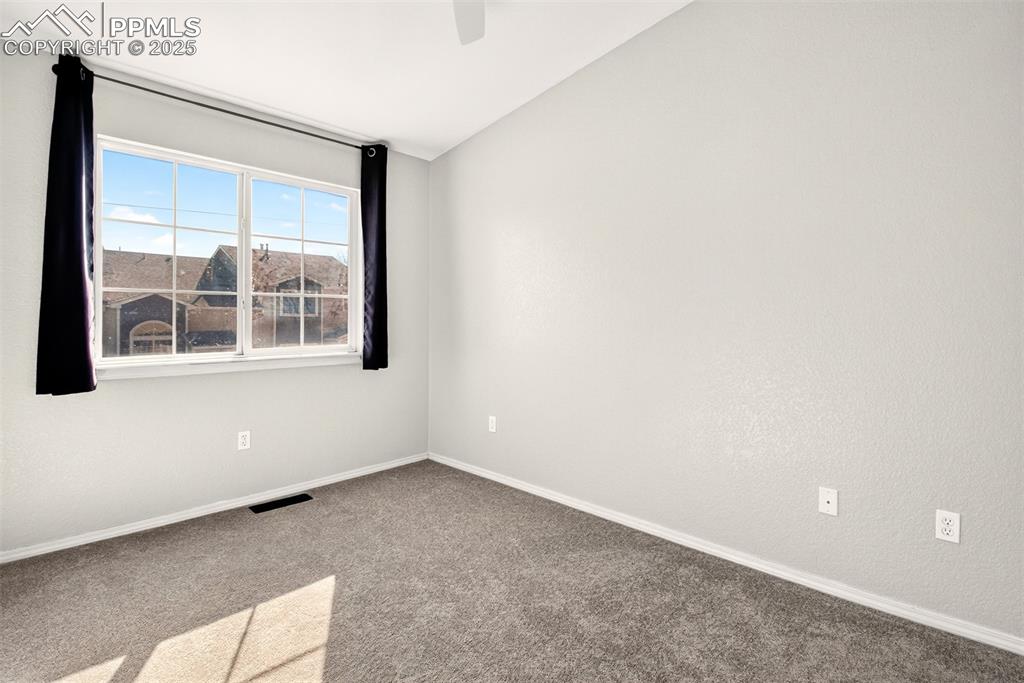 Carpeted spare room with lofted ceiling and a ceiling fan