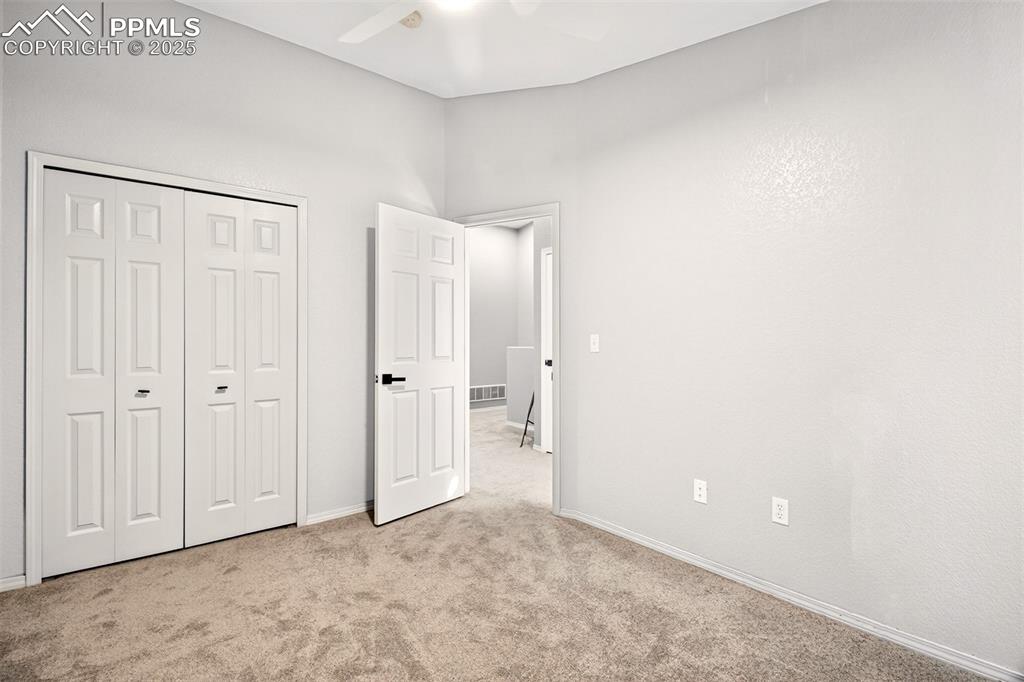 Unfurnished bedroom with light carpet, a ceiling fan, and a closet