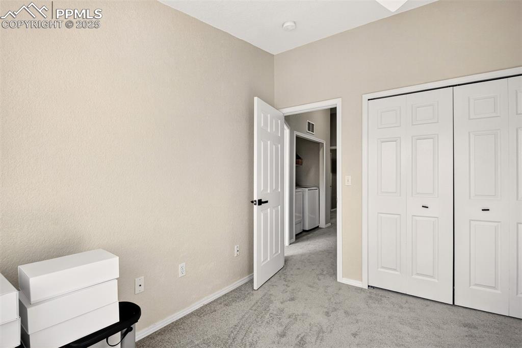 Unfurnished bedroom with light colored carpet, washer and dryer, and a closet