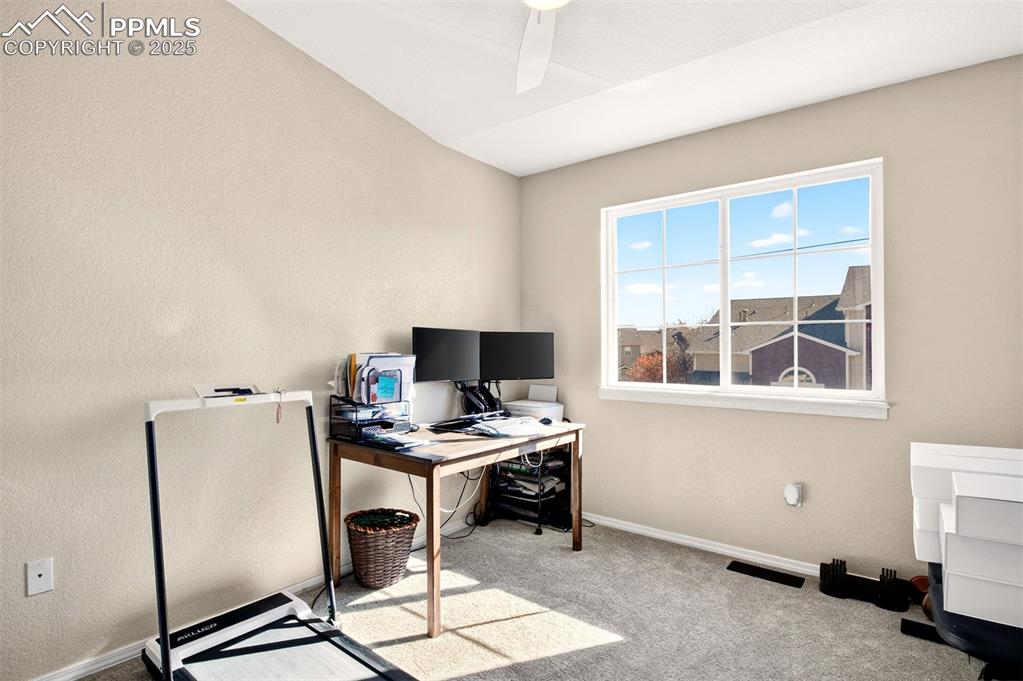 Office with carpet flooring, a textured wall, and ceiling fan