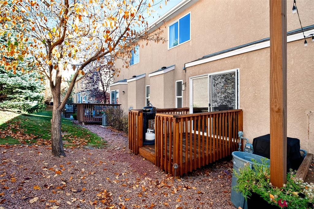 Rear view of house featuring stucco siding and a wooden deck