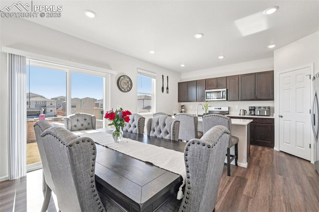 Dining room with dark wood-style flooring and recessed lighting