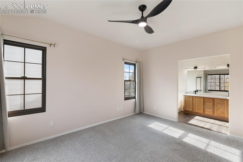 Unfurnished bedroom featuring light colored carpet, multiple windows, and ceiling fan