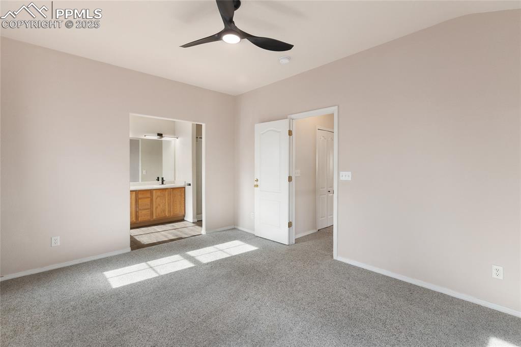 Unfurnished bedroom with light colored carpet, connected bathroom, and ceiling fan
