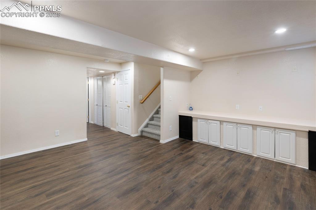 Finished below grade area with stairs, dark wood-type flooring, and recessed lighting