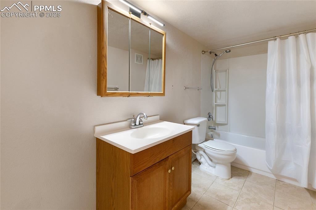 Full bath featuring vanity, shower / bath combo, and light tile patterned floors
