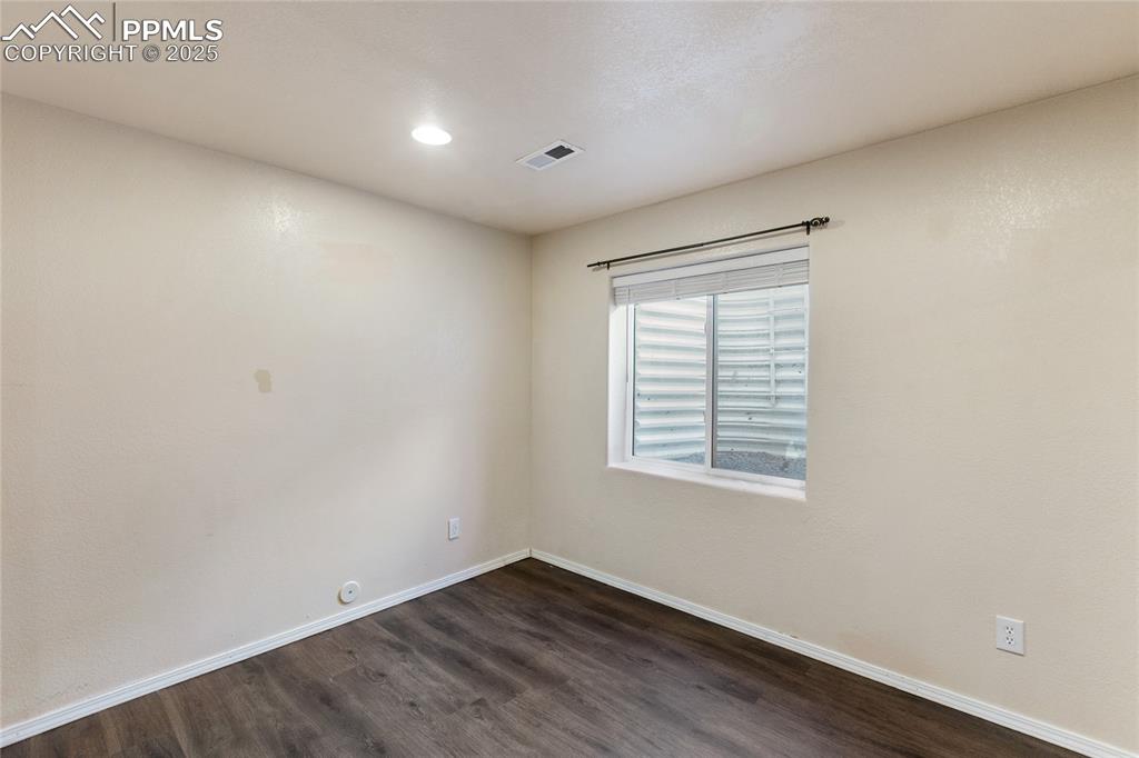 Empty room with dark wood-style flooring and recessed lighting