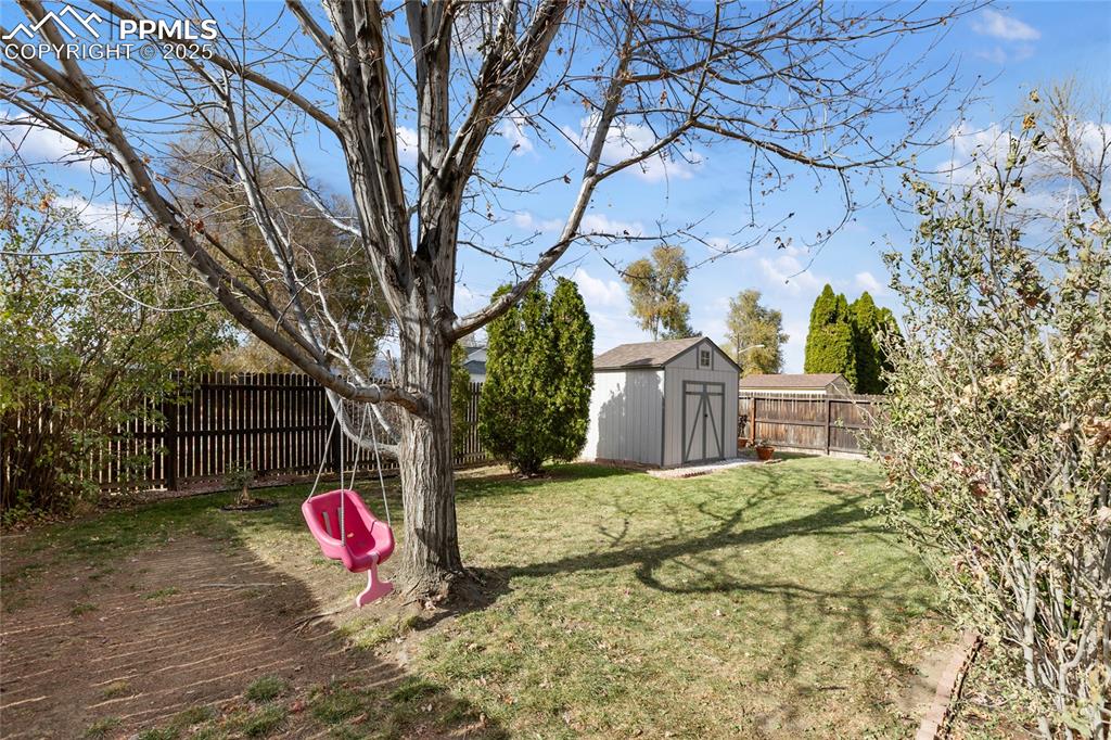 Fenced backyard featuring a storage shed