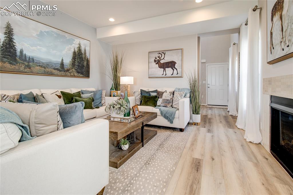 Living room with light wood-style floors, a tiled fireplace, and recessed lighting