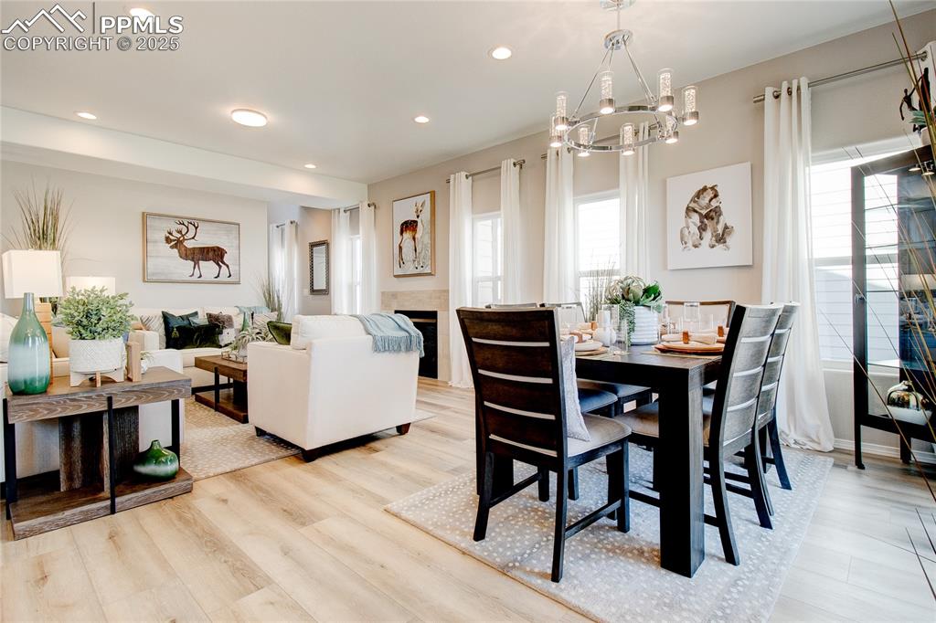 Dining room featuring recessed lighting, a tiled fireplace, light wood-style floors, and a chandelier