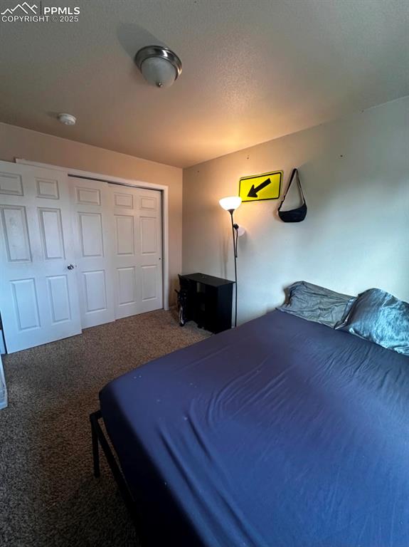Carpeted bedroom featuring a closet and a textured ceiling