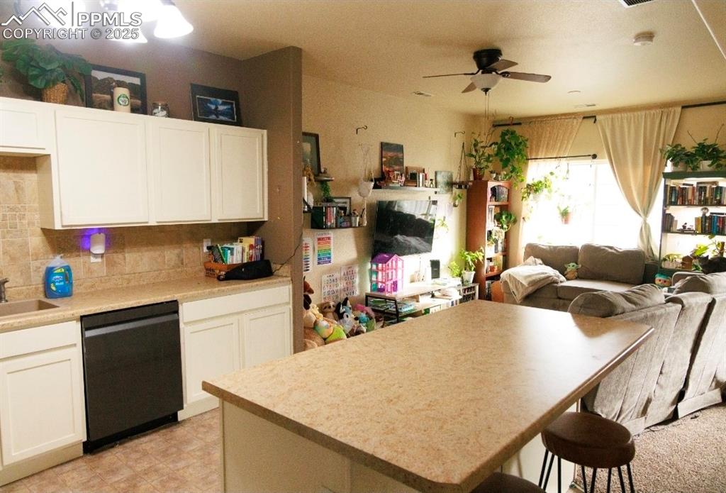 Kitchen featuring open floor plan, white cabinetry, and dishwasher