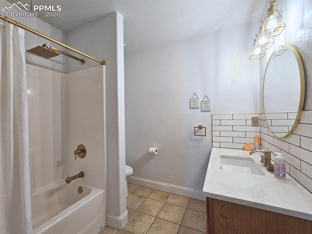 Bathroom (3) with rain shower / tub combo, custom backsplash, mirror, lighting, and quartz sink.  