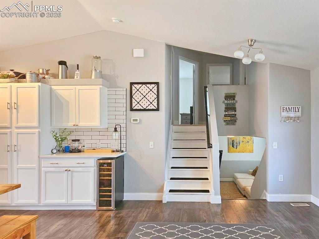 Bar to the left with a built-in cabinet for phone charging, wine cooler, and staircase that will take your upstairs.