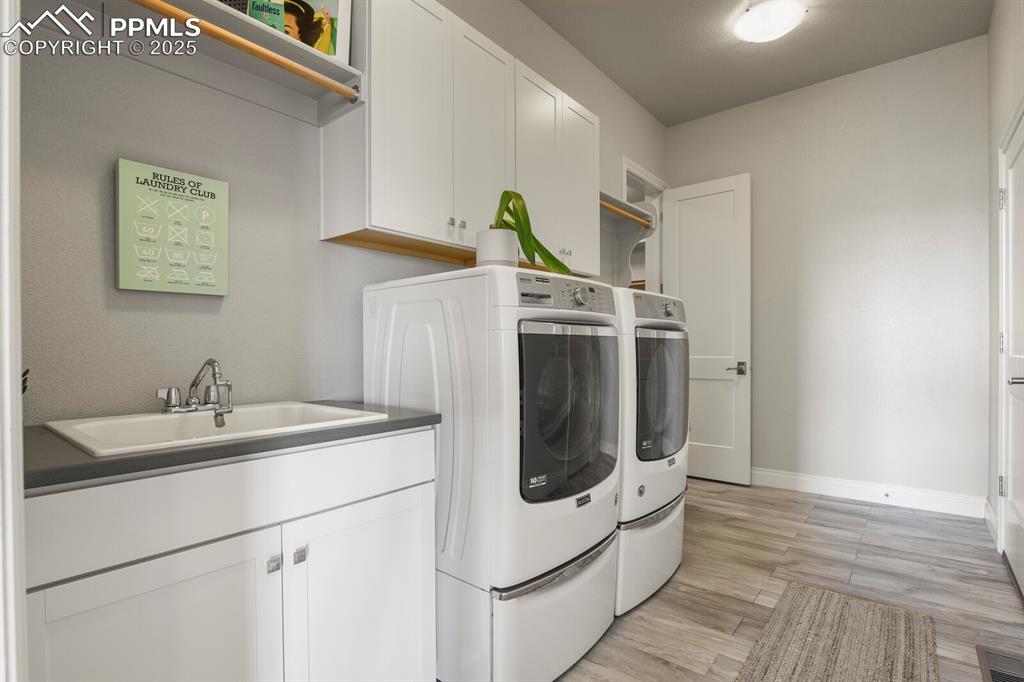 Main level laundry room with sink and access to primary walk-in closet and garage 