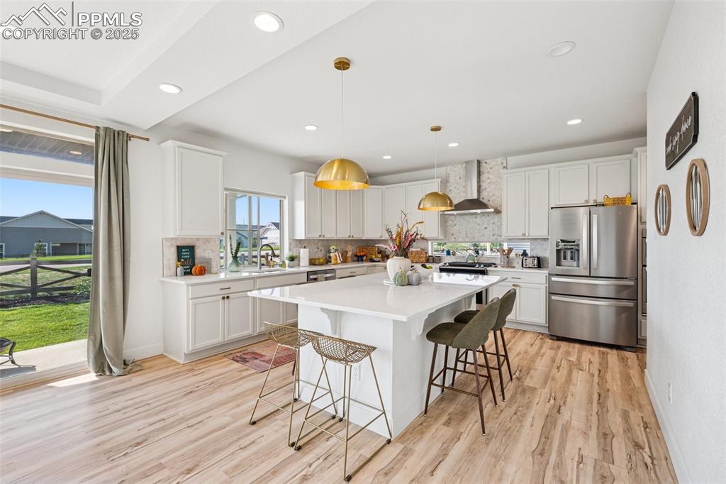 Kitchen with decorative backsplash, a kitchen breakfast bar, stainless steel appliances, decorative light fixtures, and a kitchen island