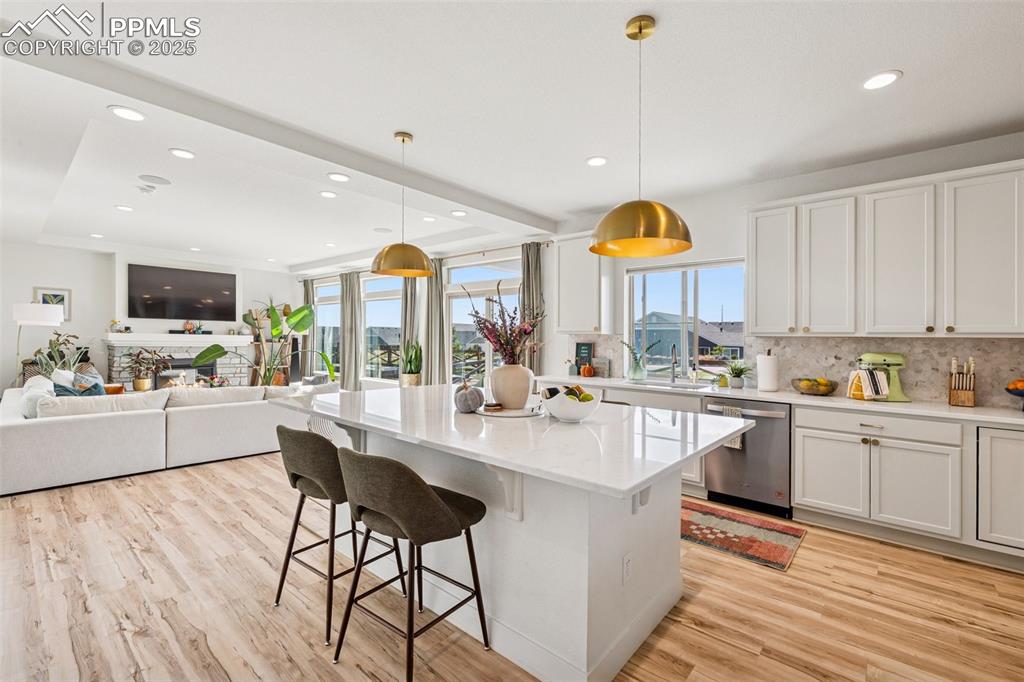 Kitchen featuring white cabinets, decorative light fixtures, tasteful backsplash, a kitchen bar, and recessed lighting