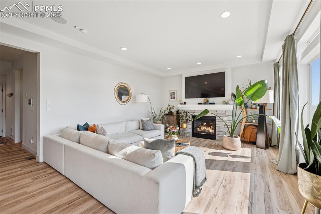 Living room with a fireplace, light wood-style floors, and recessed lighting