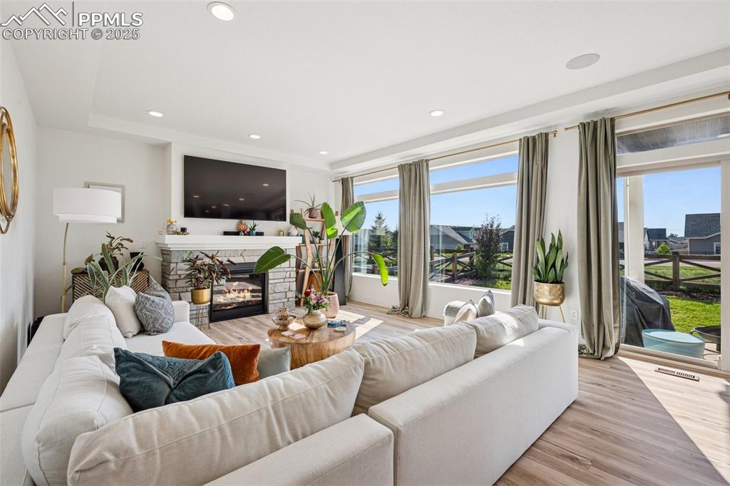 Living room with a fireplace, light wood finished floors, and recessed lighting