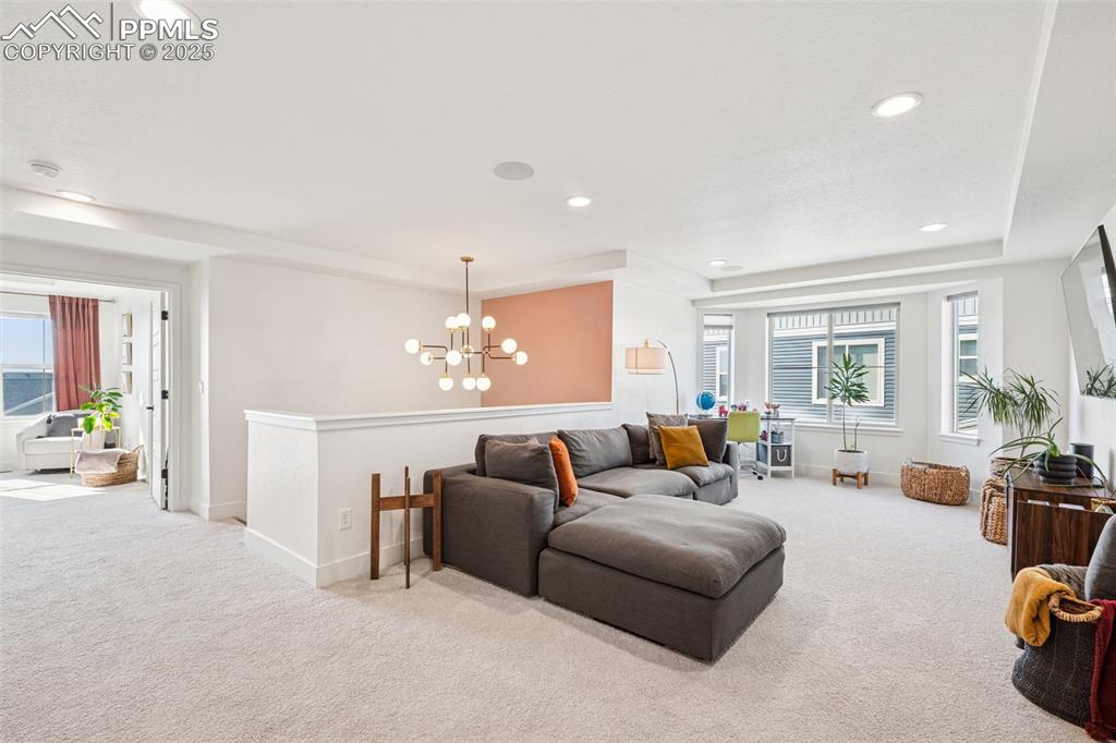 Carpeted living area with recessed lighting, a chandelier, and a tray ceiling