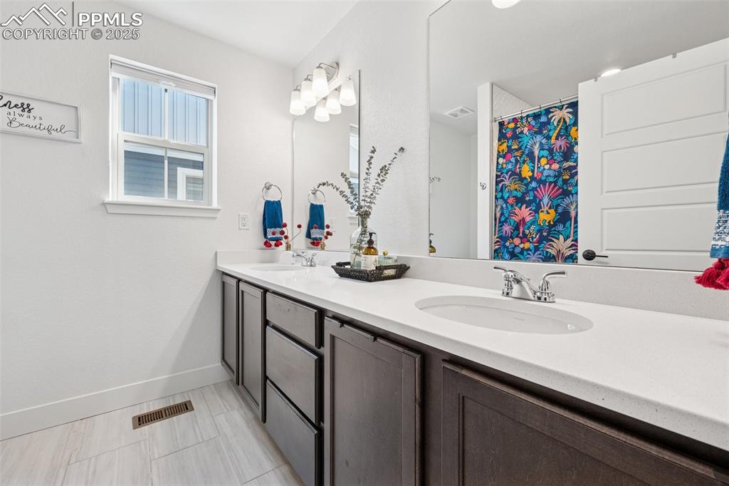Bathroom featuring double vanity, a shower with curtain, and light tile patterned floors