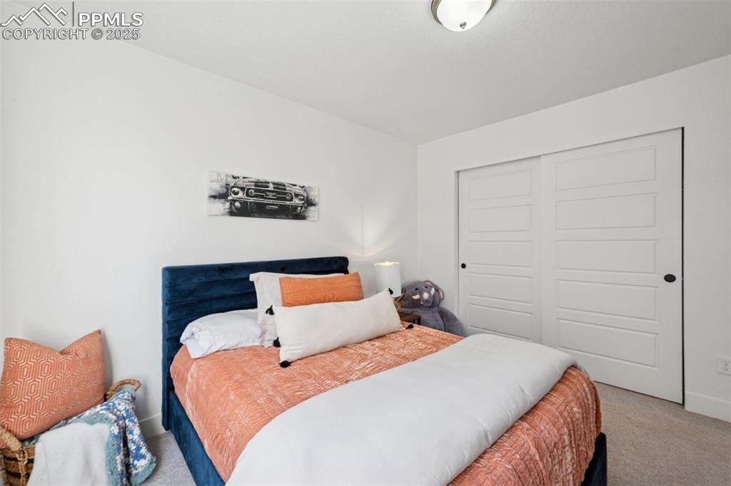 Carpeted bedroom with a closet and baseboards
