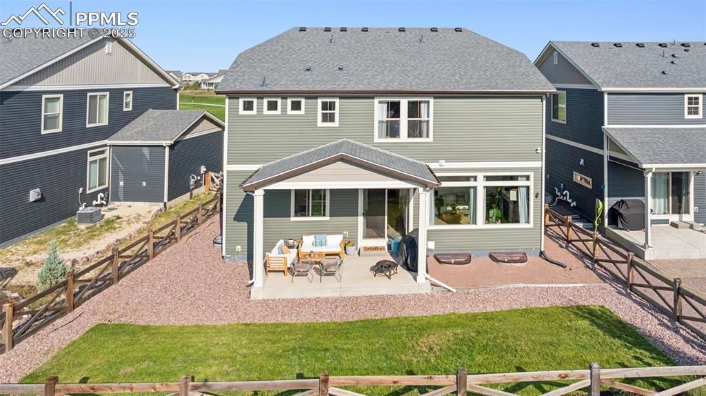 Rear view of house featuring a patio, a fenced backyard, a residential view, and roof with shingles