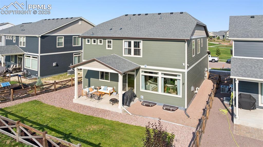 Rear view of property featuring a patio area, a residential view, an outdoor living space, roof with shingles, and a fenced backyard