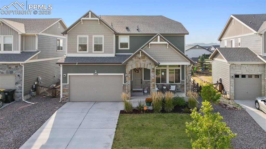 Craftsman-style home featuring stone siding, roof with shingles, a residential view, and concrete driveway