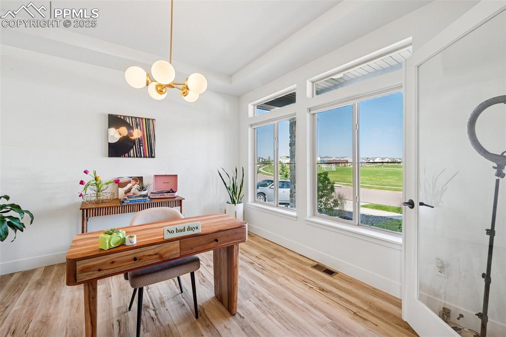 Office area featuring light wood-style floors and a chandelier