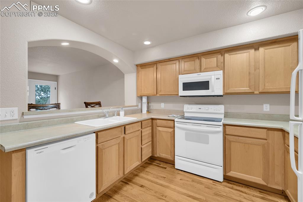 Kitchen with white appliances, light countertops, light wood finished floors, and recessed lighting
