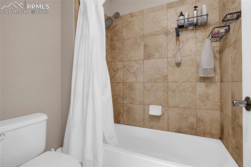 Bathroom featuring toilet and shower / bath combo with shower curtain