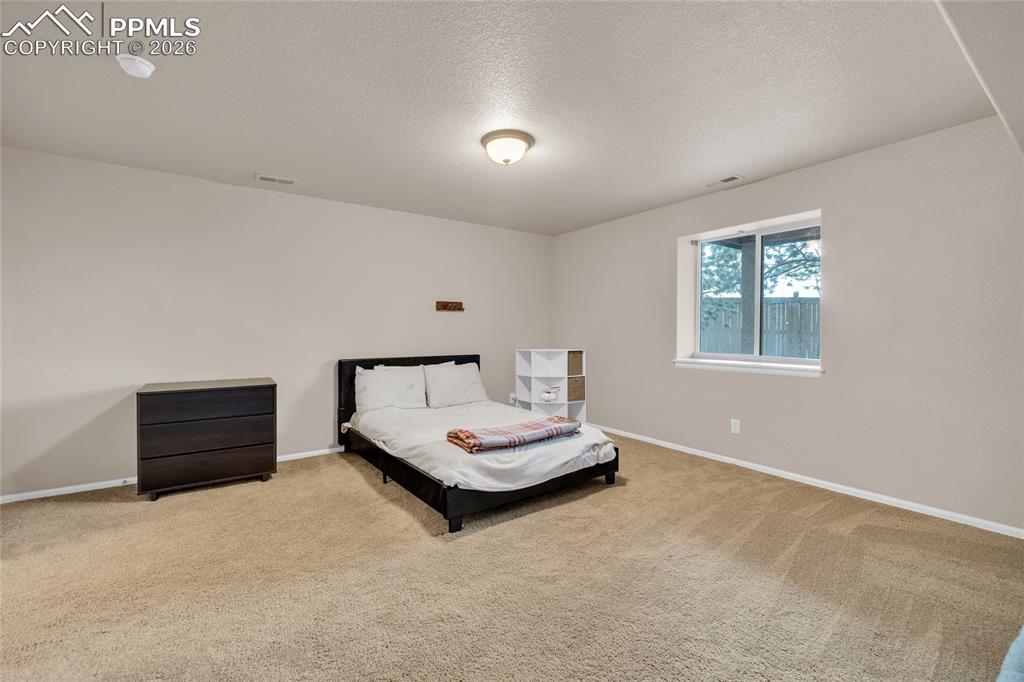 Carpeted bedroom with a textured ceiling and baseboards