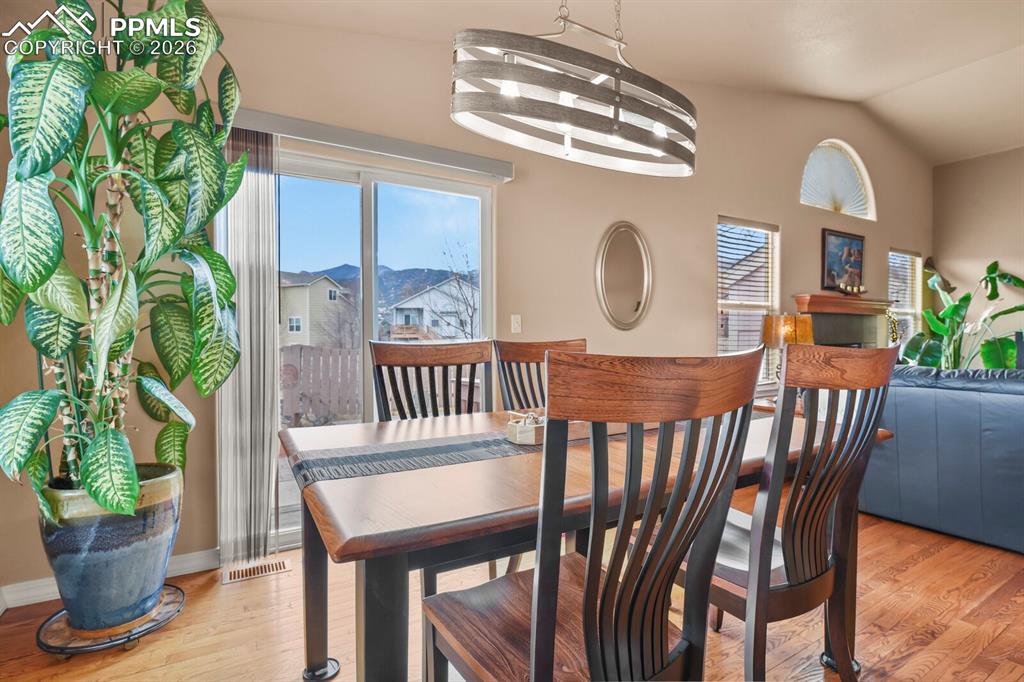 Dining area featuring hardwood floors, chandelier and slider to the outside patio area and backyard. 