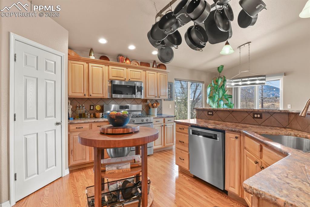 Kitchen with stainless steel appliances, dark stone counters, and light wood finish cabinets