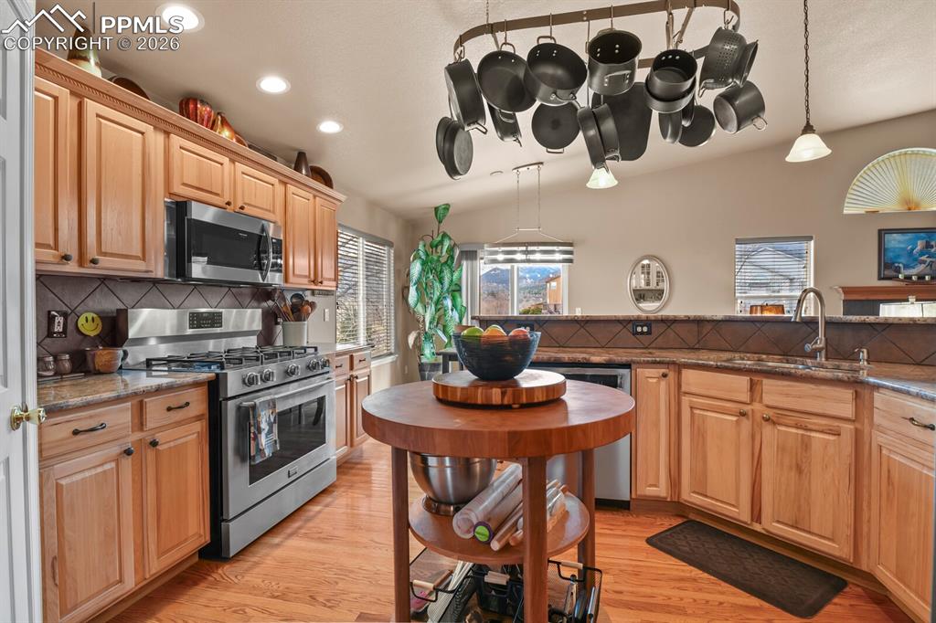 Kitchen featuring tasteful backsplash, stainless steel appliances, dark stone counters, and light wood finished floors