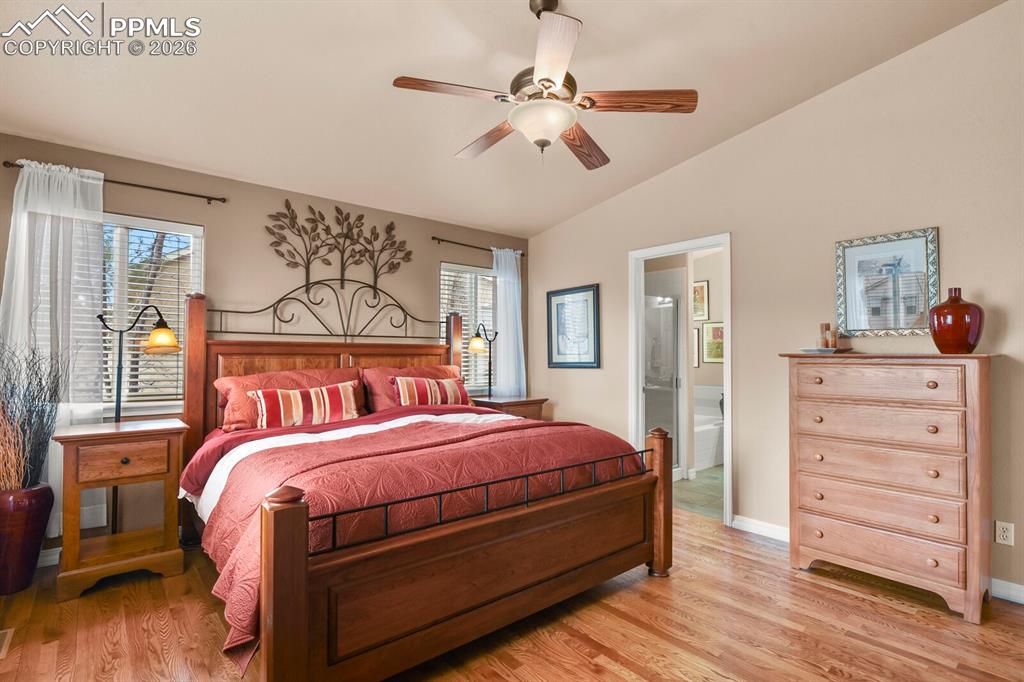  Primary Bedroom featuring hardwood floors, lofted ceiling, ceiling fan, and ensuite bathroom