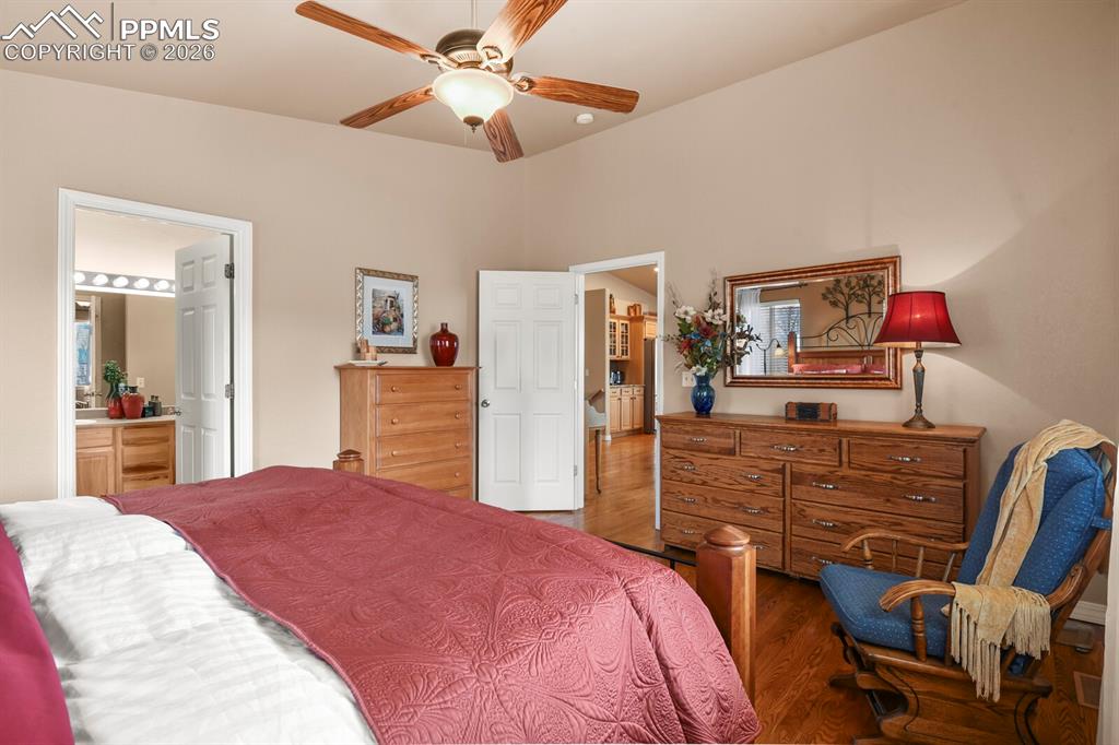 Bedroom featuring wood finished floors, a ceiling fan, and ensuite bathroom