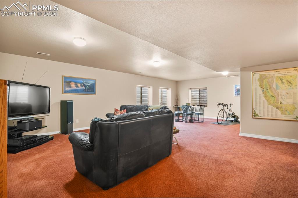Huge basement family room area with card/game table area and workout area.  Carpet.