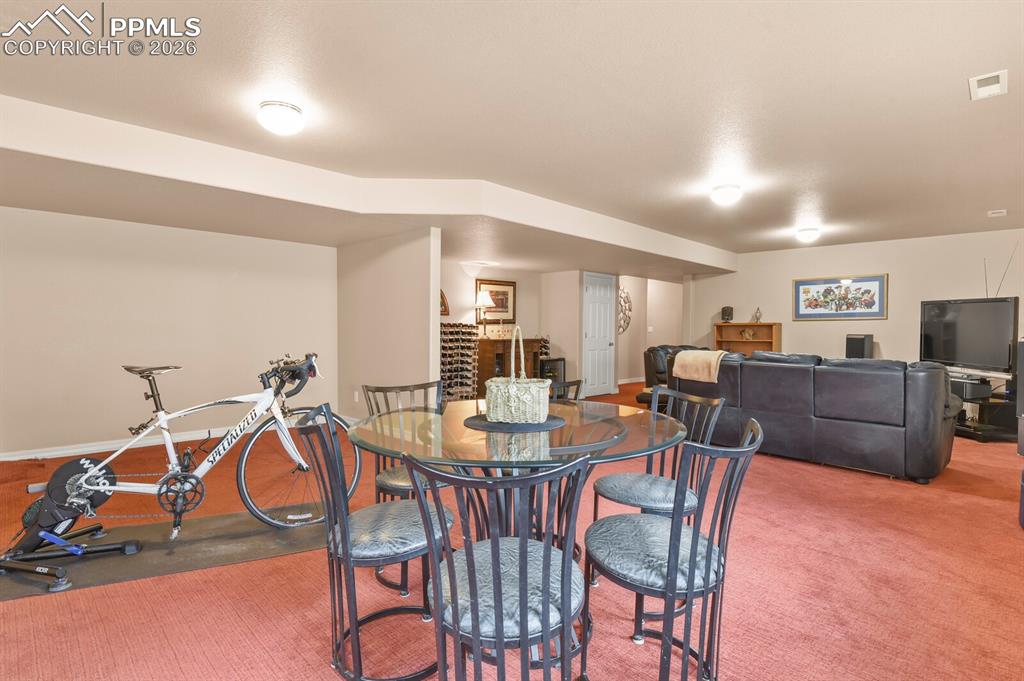 Basement Family room space showing the exercise area and card/game table.  Carpet.