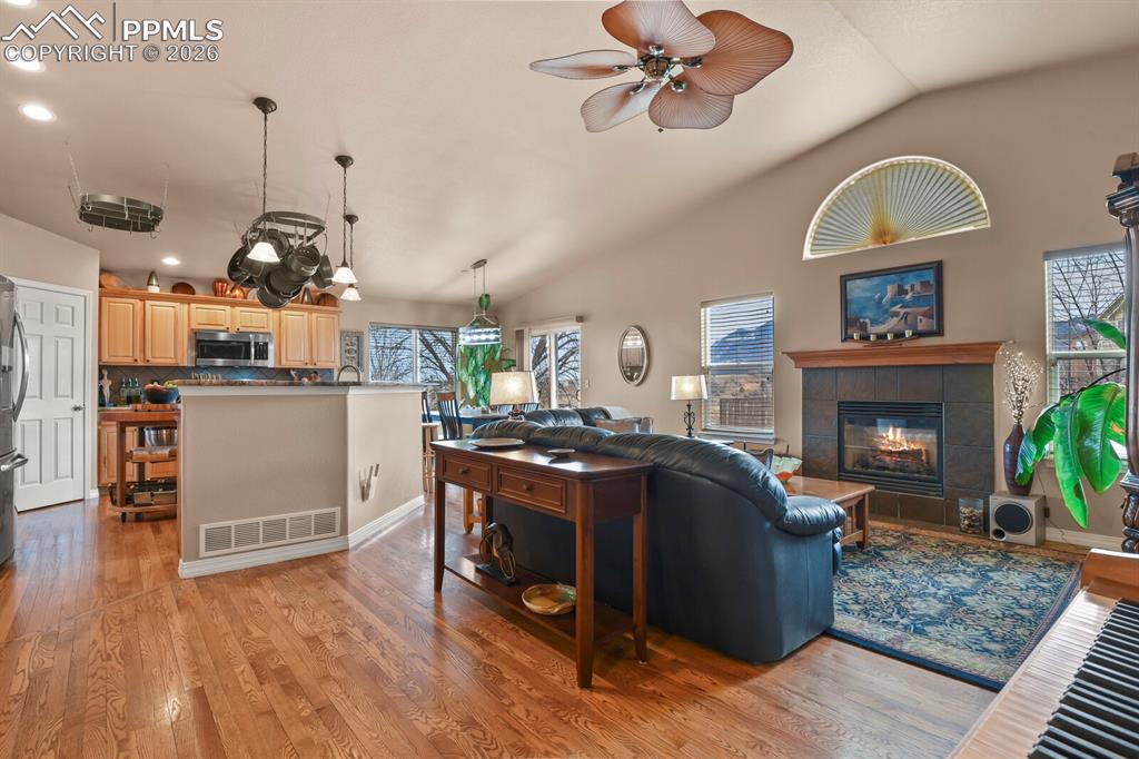 Open plan living: Living room with lofted ceiling, light wood-style flooring, a gas fireplace, recessed lighting, and natural light. Open to the Kitchen and Dining Areas.