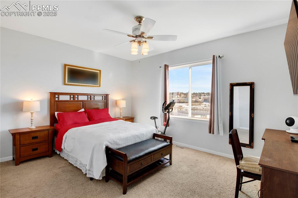 Bedroom featuring light colored carpet, baseboards, and ceiling fan