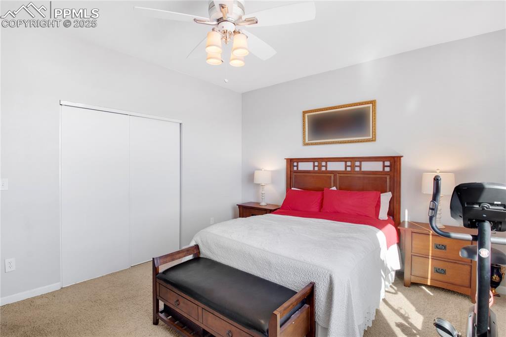Carpeted bedroom with ceiling fan and a closet