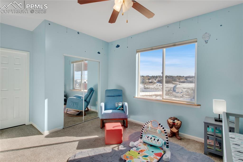 Recreation room with carpet flooring, a ceiling fan, and baseboards