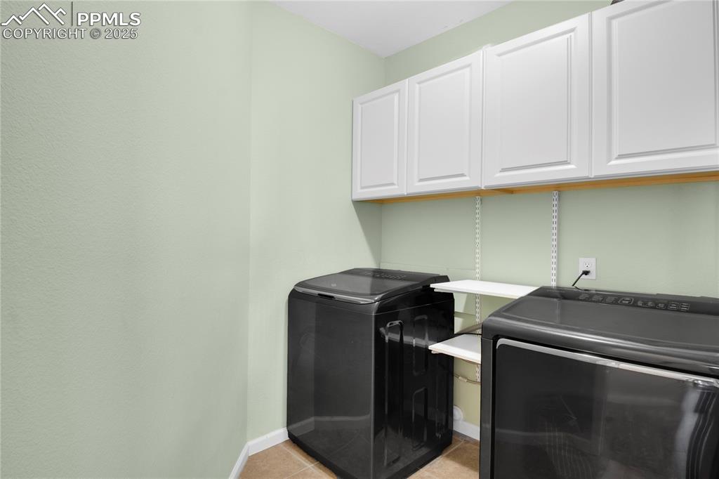 Laundry area featuring cabinet space, baseboards, and light tile patterned floors