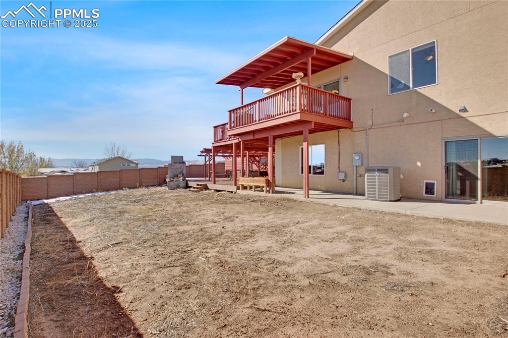 Rear view of property with stucco siding, cooling unit, a fenced backyard, a deck, and a patio area