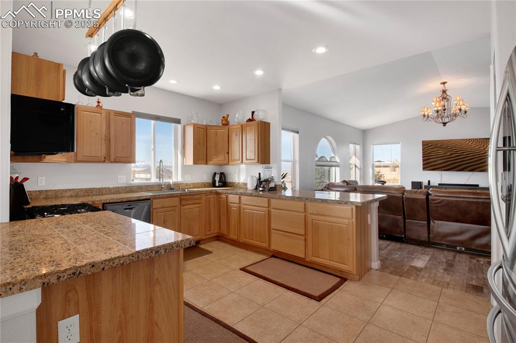Kitchen featuring tile countertops, stainless steel appliances, a sink, a peninsula, and a chandelier