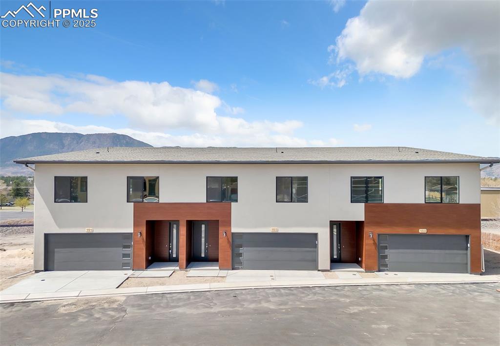 Modern home featuring an attached garage, a mountain view, and stucco siding