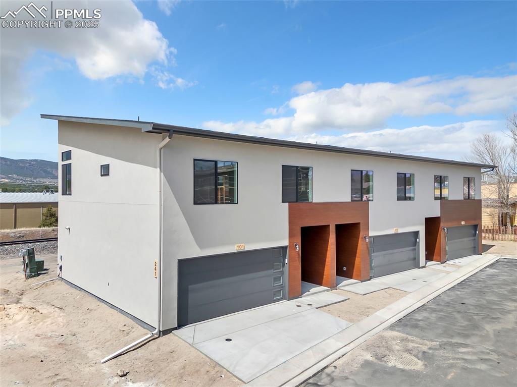 Modern home with an attached garage, concrete driveway, and stucco siding